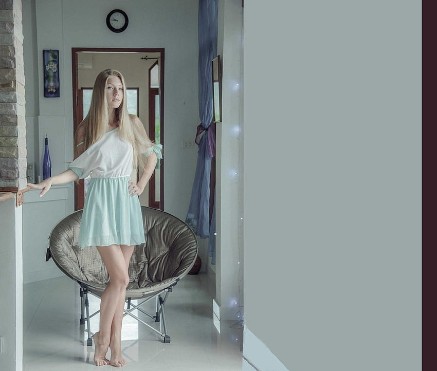 Anjelica Ebbi, blau, blond, Holzverkleidung über Türen, barfuß, runder Stuhl, Weinflasche, im Flur, hellblaues Minikleid, Uhr HD-Hintergrundbild