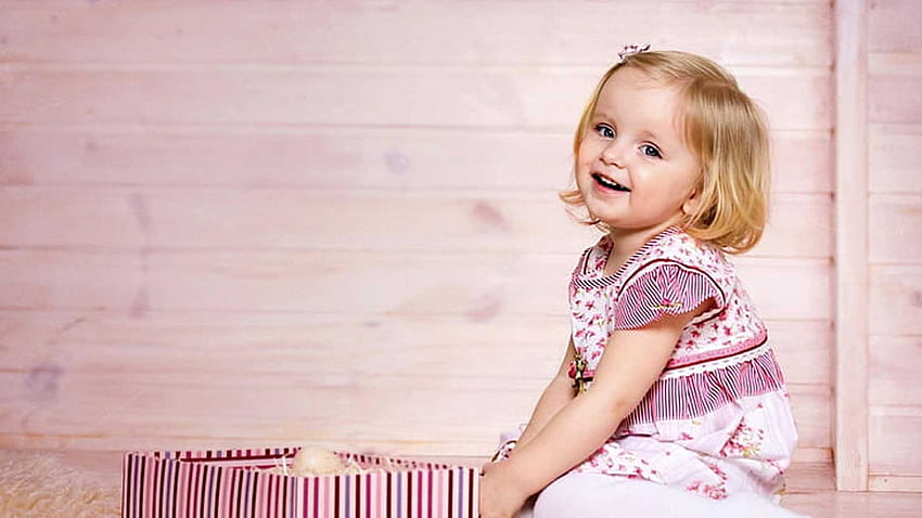 かわいい笑顔の小さな女の赤ちゃんは、明るいピンクの壁の背景に座っている白いピンクのドレスを着ています かわいい 高画質の壁紙