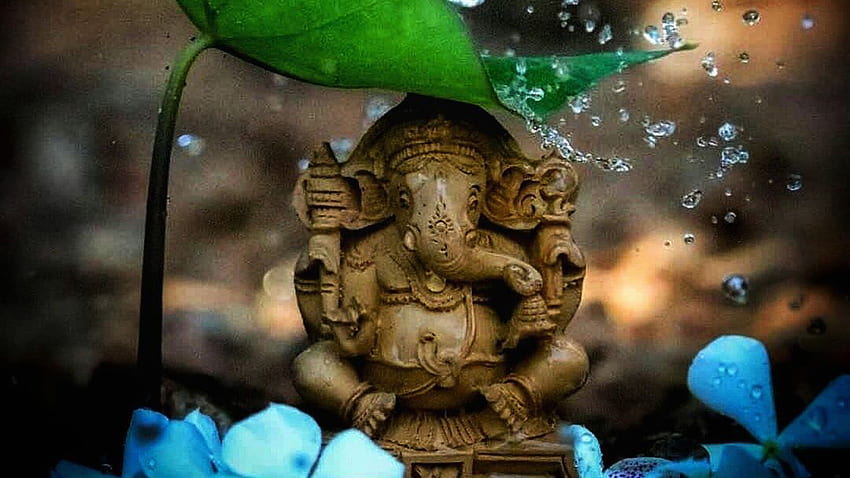 Linda estátua de Ganesh sob folha verde respingos de água em fundo desfocado bonito papel de parede HD