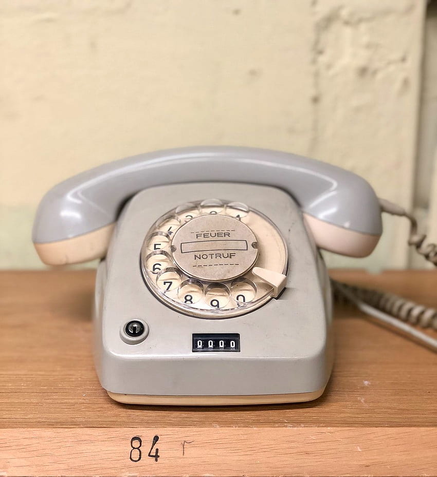 teléfono rotatorio gris sobre mesa marrón fondo de pantalla del teléfono