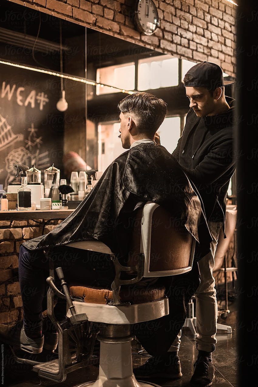 Junger Friseur, der dem Kunden einen klassischen Haarschnitt im Vintage-Friseursalon gibt HD-Handy-Hintergrundbild