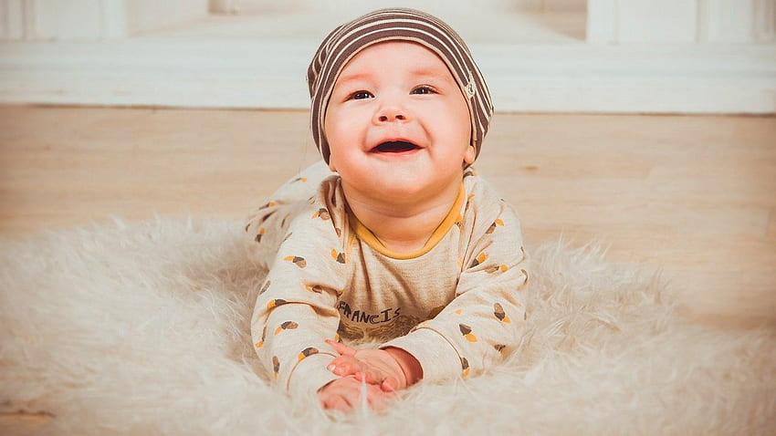 Gülen Sevimli Erkek Bebek Beyaz Kürk Kumaş Sarı Beyaz Elbise Ve Sevimli Şapka Giyiyor Üzerinde Uzanıyor HD duvar kağıdı