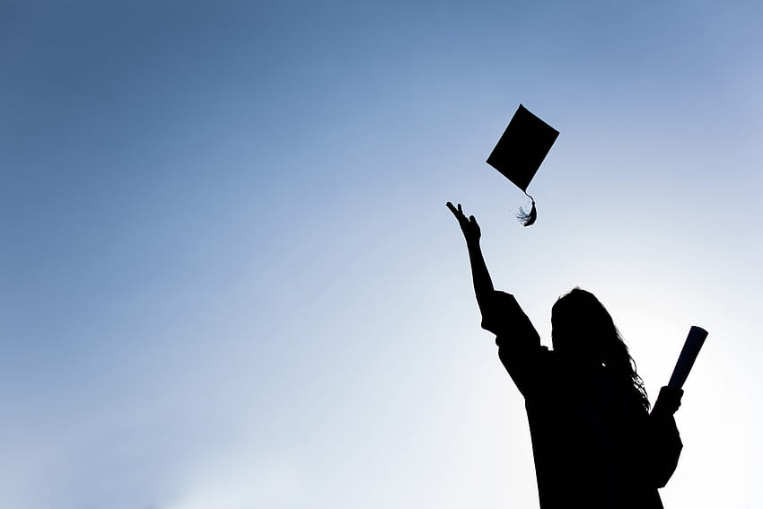 Estudiantes graduados arrojando sombreros sobre el cielo azul - Asociación de Educación de Michigan fondo de pantalla