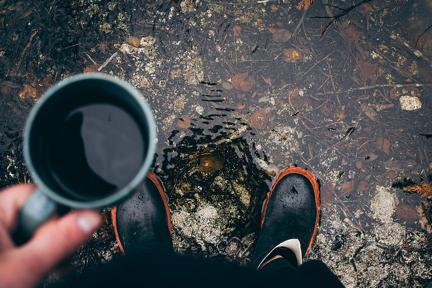 / a person wearing rain boots stands in a puddle looking down and holding coffee, morning coffee HD wallpaper