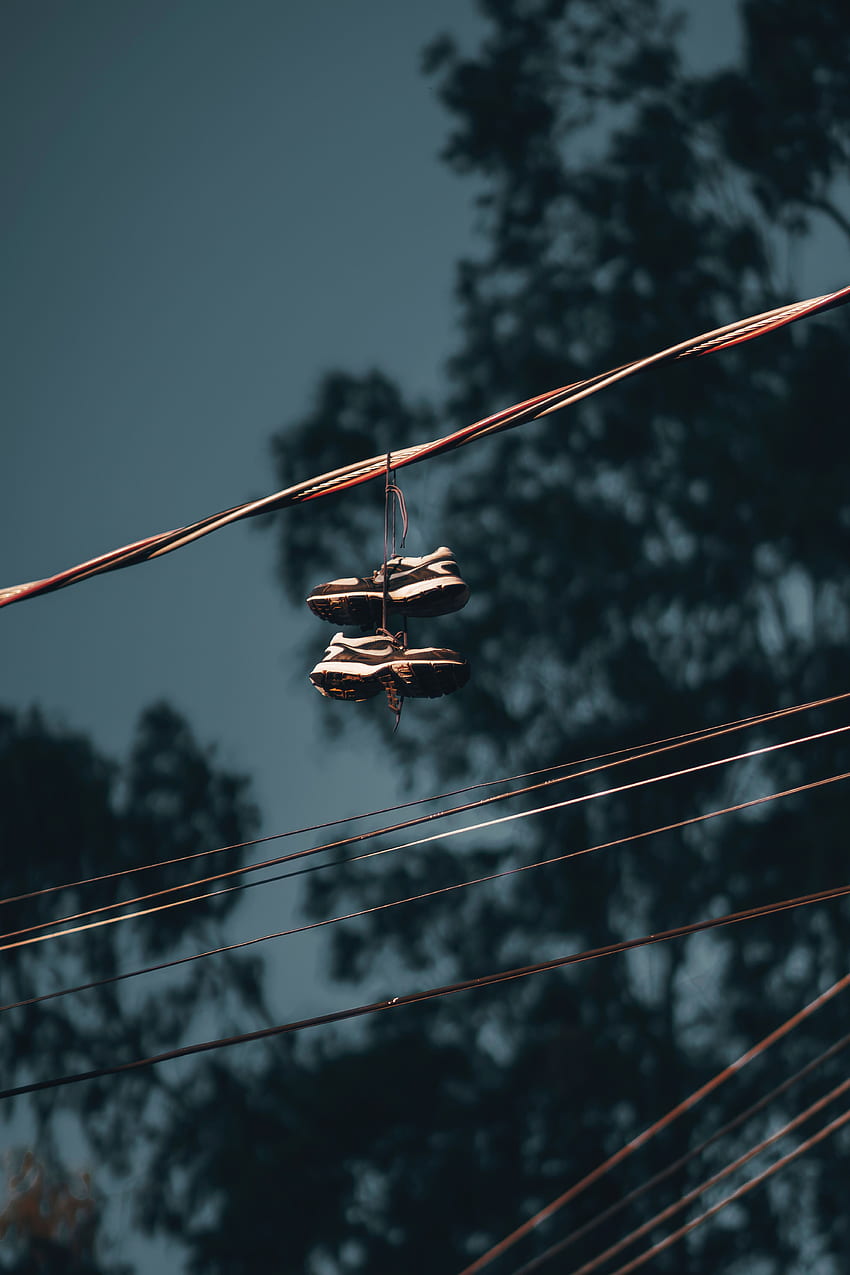 Sneakers hanging on metal chimney near wires · Free Stock Photo