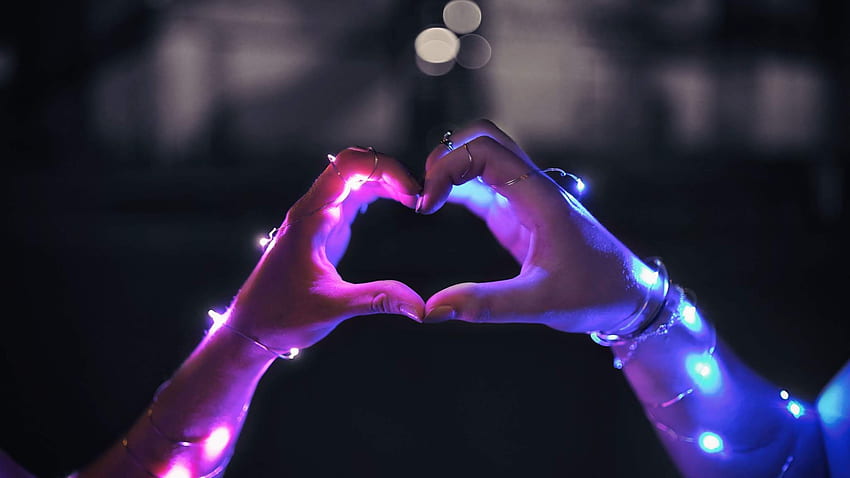 Il LED del cuore di amore illumina le mani Sfondo HD