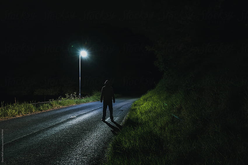Una siniestra figura encapuchada, mirando una farola de noche por Dave Wall - Noche, persona, figura oscura encapuchada fondo de pantalla