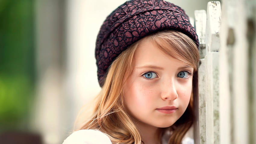 Cute Girl Is Standing Near White Gate Wearing Woolen Cap With Ash Eyes In Blur Background Cute HD wallpaper