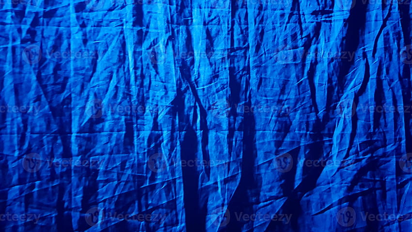Fabric blue background for your design. A blue ray of light diagonally  illuminates the dark black