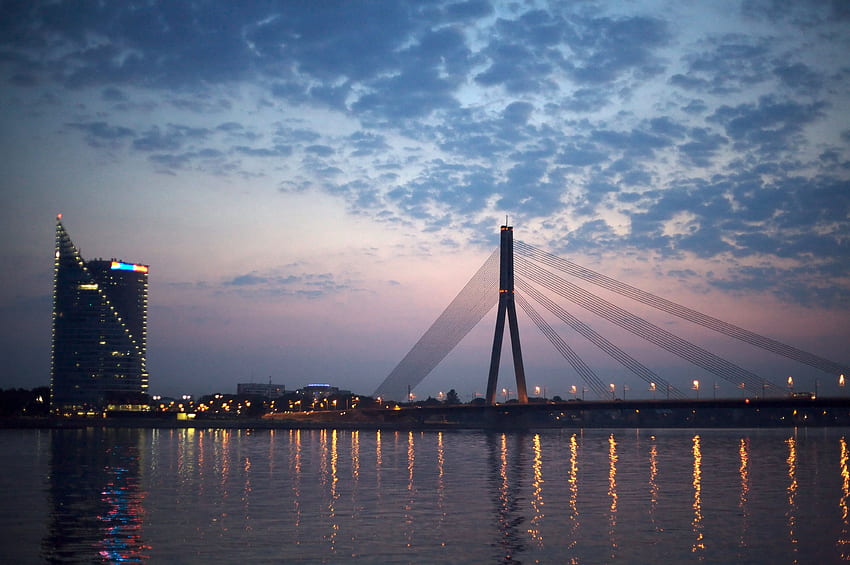 Orange beleuchtete Brücke unter bewölktem Himmel, Riga HD-Hintergrundbild