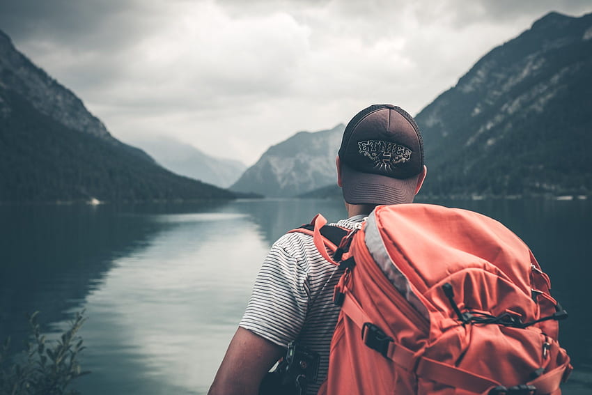/ pejalan kaki dengan tas punggung yang berat memandang pegunungan dan air yang tenang, backpacker gunung Wallpaper HD