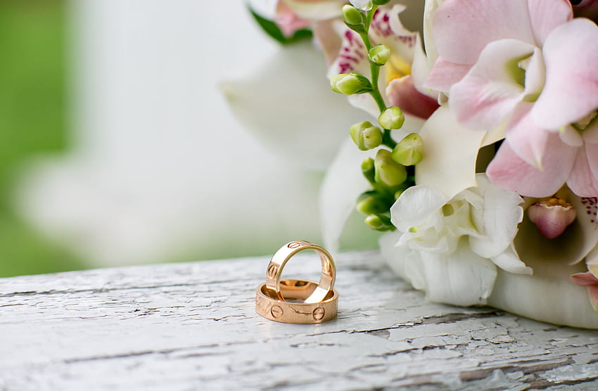 2 つの金の結婚指輪が花とテーブルの上にあります。 高画質の壁紙