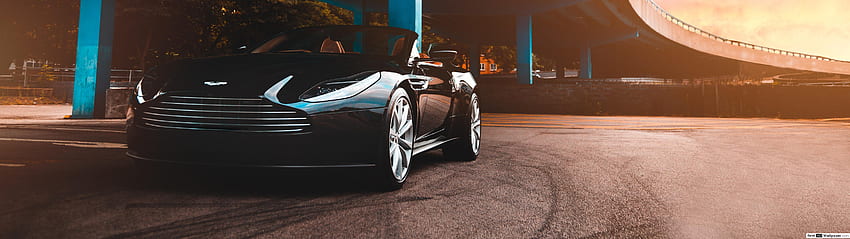 Czarny samochód Aston Martin Cabrio DB11 zaparkowany obok niebieskiego betonowego mostu, samochód 5120x1440 Tapeta HD