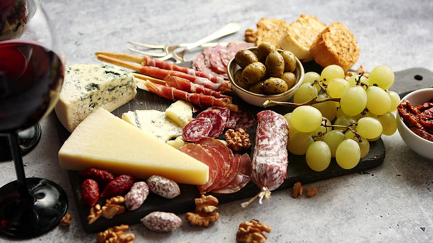 Antipasti-Plattenaufschnitt und Käseplatte mit Trauben, Wein, verschiedenen Käsesorten, Grissini-Brotstangen auf weißem rustikalem Hintergrund. Ansicht von oben Stock Video Footage, Aufschnitt HD-Hintergrundbild