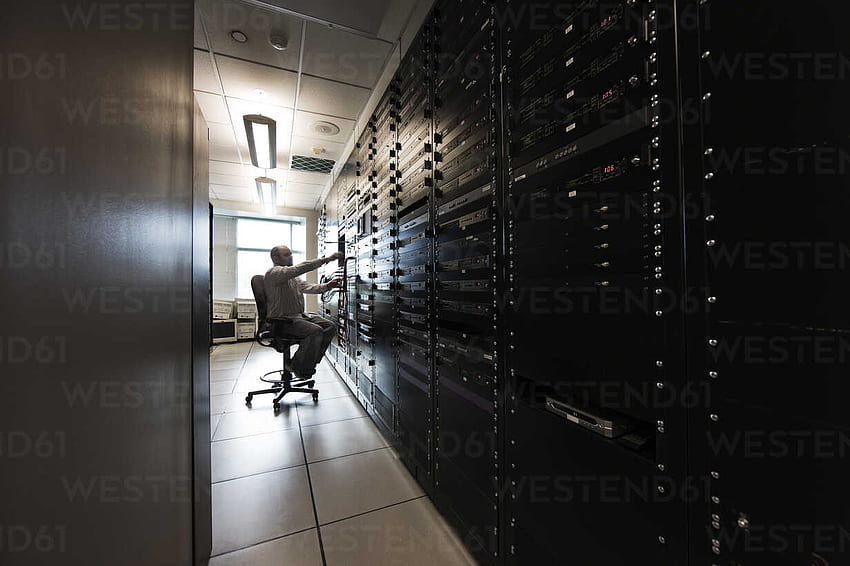 Computer server room racks with technician in background. stock HD wallpaper
