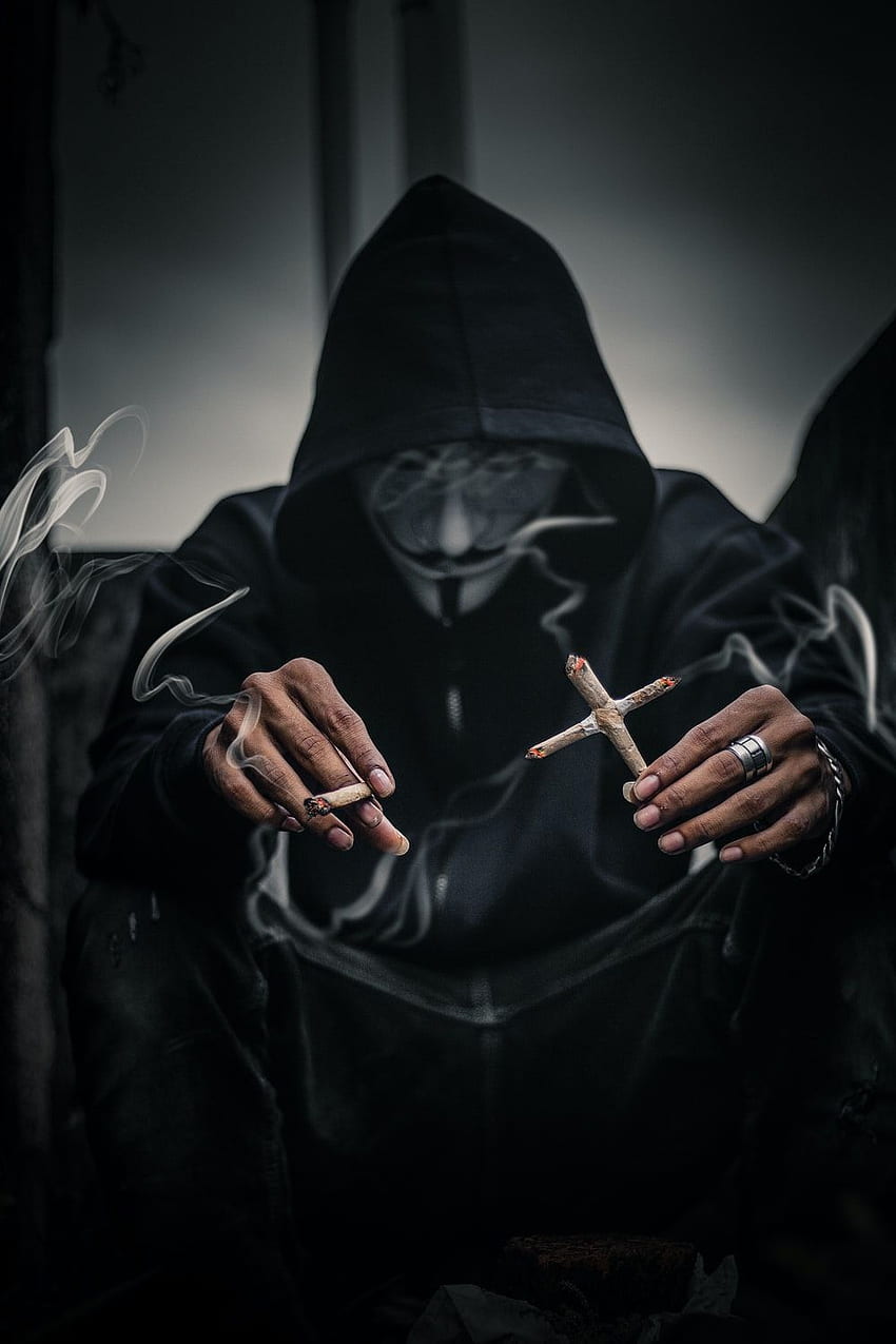 Persona in maschera di Guy Fawkes che tiene sigarette accese a forma di croce alla sua sinistra con Joice acceso sulla mano destra - dito Sfondo del telefono HD