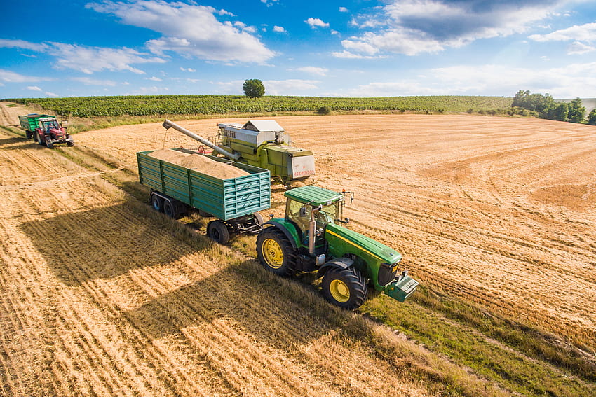 Combine Harvester Pouring Grain into Towed by Tractor Stock HD wallpaper