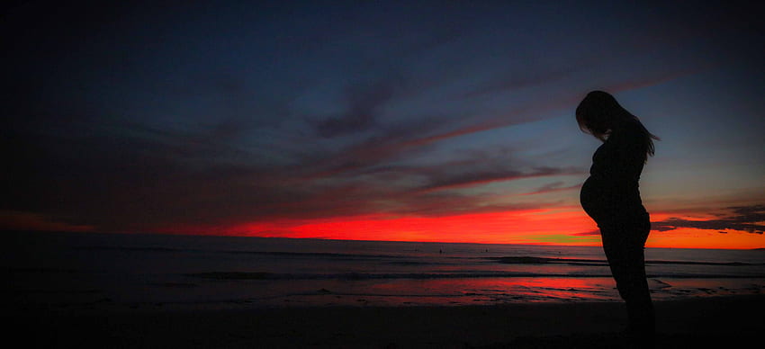Mujer embarazada cerca del mar durante la puesta de sol, Embarazo fondo de pantalla