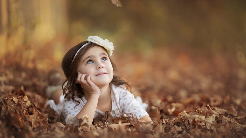 Cute Little Girl leży na suchych liściach na sobie białą sukienkę patrząc w rozmycie tła Cute Tapeta HD