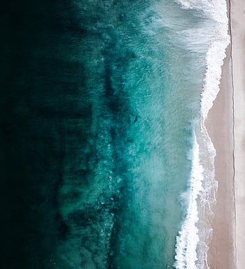 Aerial top down footage of white waves and emerald green ocean water ...