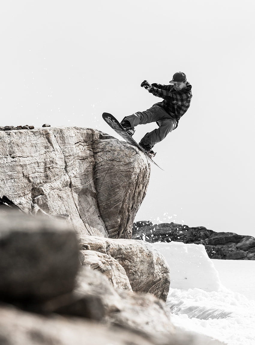 uno snowboarder esegue un trucco e si ferma su un masso su un nevoso, Trick Black and White Sfondo del telefono HD
