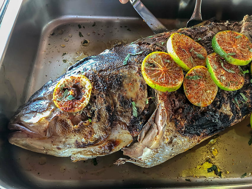 Whole grilled fish decorated with lime slices and sweet pe HD wallpaper