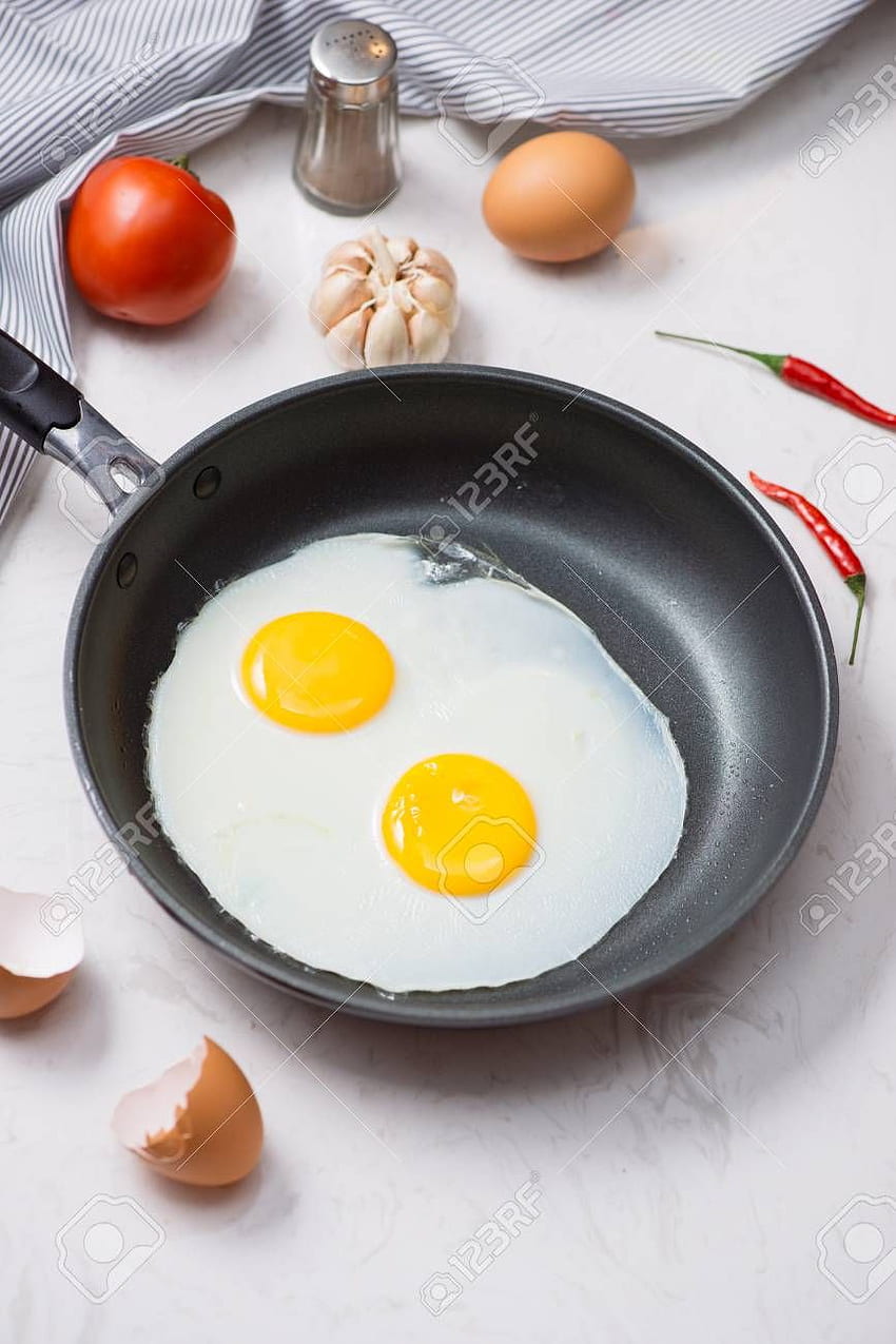 Eating in the process, fried eggs in a frying pan for breakfast on a white background. Daylight. HD phone wallpaper
