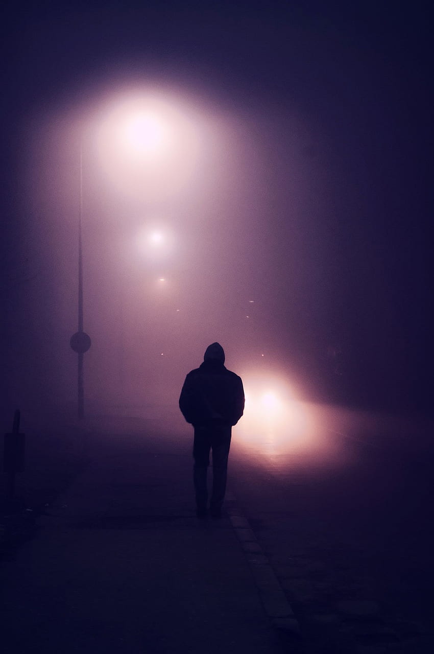 Nebel - Silhouette eines jungen Mannes, der in einem nebligen, allein gehenden Zustand die Straße hinuntergeht HD-Handy-Hintergrundbild