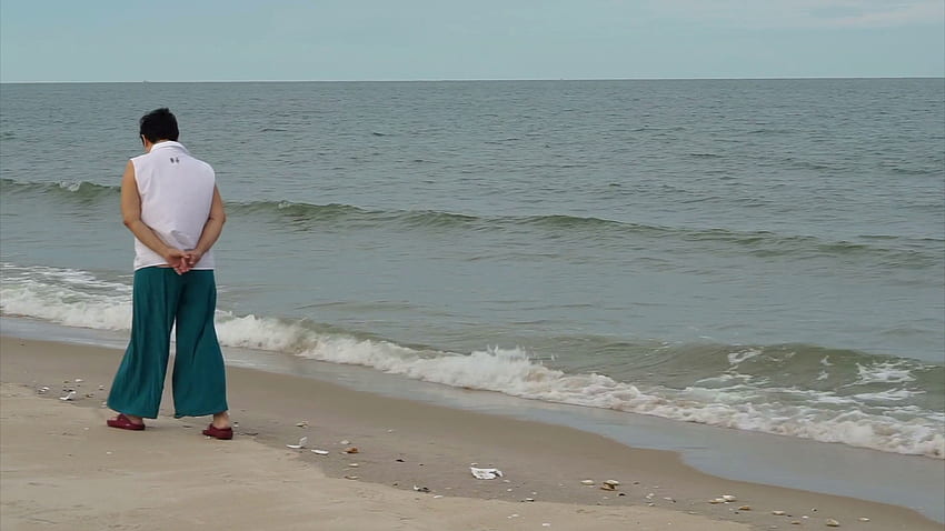 Asian senior woman walking alone along the beach enjoying nature Stock Video Footage HD wallpaper