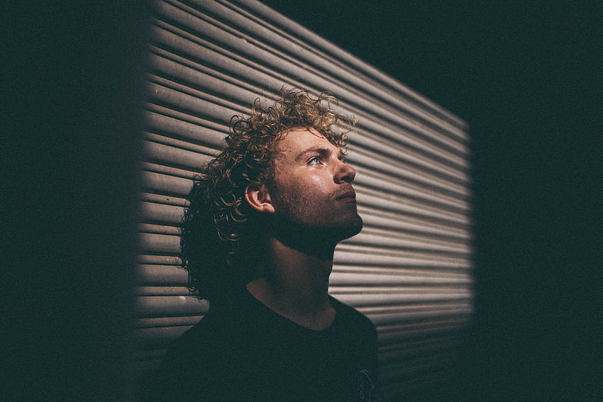 / a man with curly hair in shadow leans his head back against a wall, man leaning head on wall, Curly Hair Men HD wallpaper