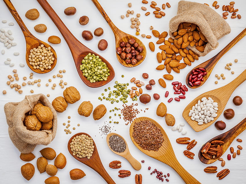 Various legumes and different kinds of nuts in spoons. Walnuts kernels , hazelnuts, almond , brown pinto , soy beans , flax seeds , chia , red kidney beans and pecan set up on white wooden table HD wallpaper