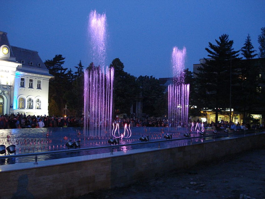 Fountain, night, windows, sidewalk, house, crowd, people, purple, lights, trees, clock, water HD wallpaper