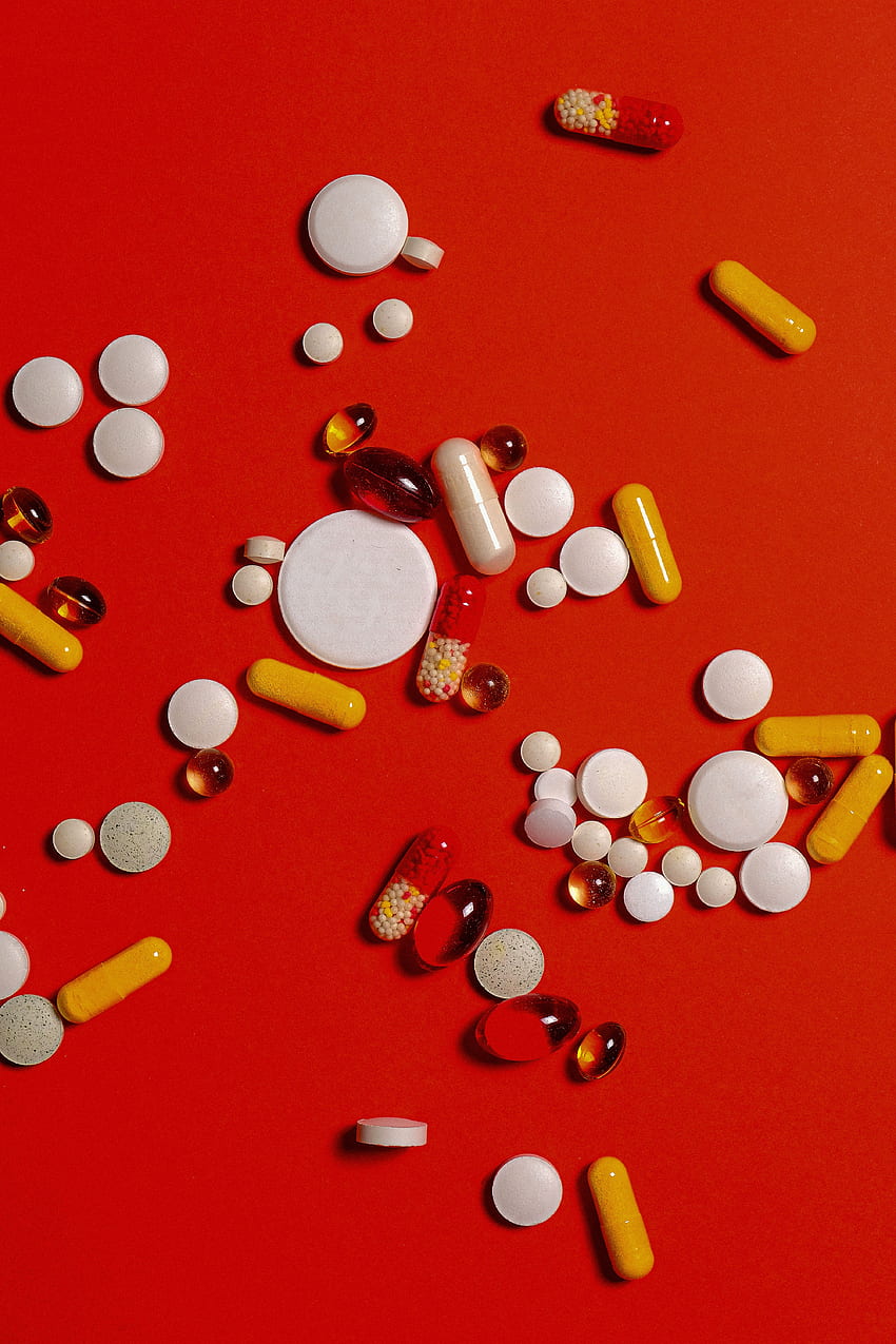赤い背景に別の薬の丸薬とカプセル · HD電話の壁紙