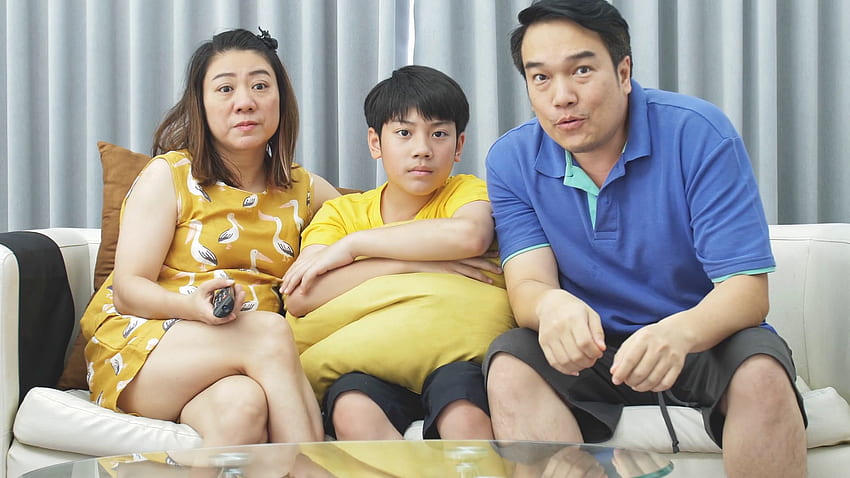 Câmera lenta da família asiática pai mãe e filho no sofá, olhando para a câmera com um sorriso no rosto. Vídeos de arquivo papel de parede HD